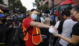 A city worker offers antibacterial gel to passing shoppers as they walk in a crowded commercial district of central Mexico City, Saturday, Dec. 5, 2020. With hospitals once again filling up with COVID-19 patients, Mexico City&#x27;s mayor on Friday urged people to stay at home as much as possible and authorized checkpoints to limit the number of people entering the capital&#x27;s colonial-era downtown at one time. (AP Photo/Rebecca Blackwell)
