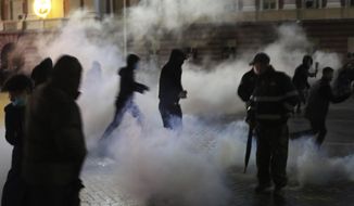 Protester walk among smoke by tear gas during clashes outside the Prime&#39;s Minister office in Tirana, Albania , on Wednesday, Dec. 9, 2020. Clashes have broken out in Tirana during a protest by hundreds of Albanians demanding the interior minister&#39;s resignation over the fatal police shooting of a 25-year-old man who had breached a coronavirus-linked curfew. (AP Photo/Hektor Pustina)