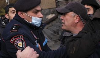 A police officer tries to detain demonstrators during a rally demanding the resignation of the country&#x27;s prime minister over his handling of the conflict with Azerbaijan over Nagorno-Karabakh in Yerevan, Armenia, Tuesday, Dec. 8, 2020.Armenian opposition politicians and their supporters have been calling for Prime Minister Nikol Pashinyan to step down ever since he signed a peace deal that halted 44 days of deadly fighting over the separatist region, but called for territorial concessions to Azerbaijan. (AP Photo/Hrant Khachatryan)