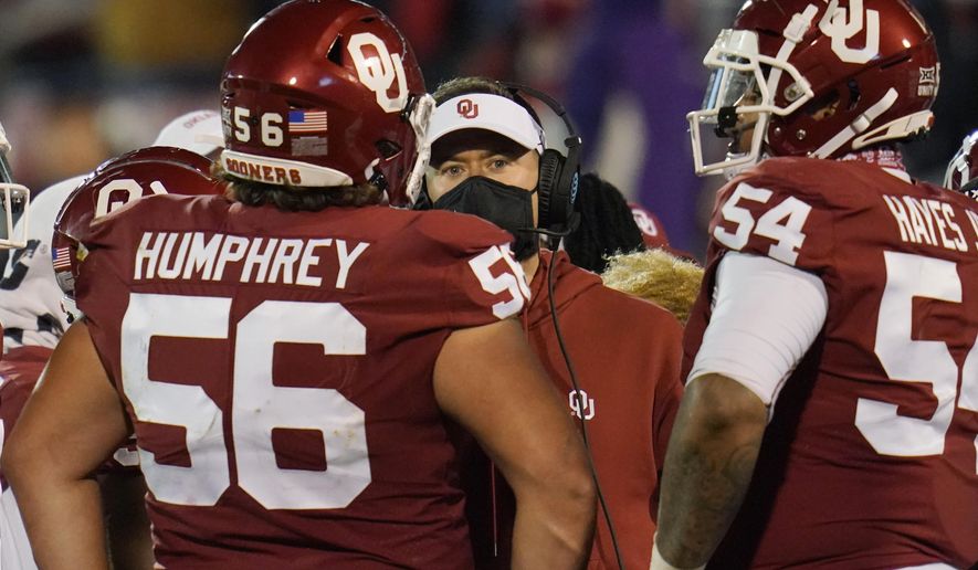 Oklahoma coach Lincoln Riley, center, talks with his players during the second half of an NCAA college football game against Baylor on Saturday, Dec. 5, 2020, in Norman, Okla. (AP Photo/Sue Ogrocki)