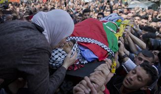 FILE - In this March 21, 2019 file photo, Wafa Manasra, mother of  22-year-old Palestinian Ahmad Manasra, kisses him goodbye during his funeral in the West Bank village of Wad Fokin, near Bethlehem. In a ruling Wednesday, Dec. 9, 2020, an Israeli military tribunal has upheld a plea bargain that avoids jail time for a soldier who killed Manasra and seriously wounded another in a West Bank shooting last year. Palestinians and Israeli rights groups have accused the military court of excessive leniency, and the deal was fiercely criticized by the victims&#39; families. (AP Photo/Nasser Nasser, File)