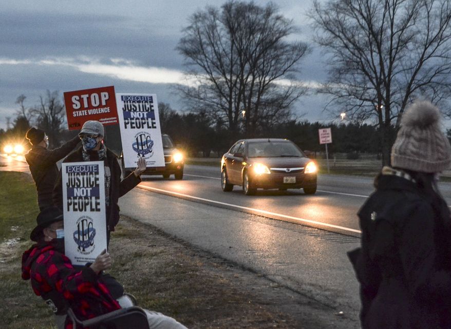 Protesters stand across Prairieton Road from the Federal Death Chamber Friday, Dec. 11, 2020 in Terre Haute, Ind. The Trump administration plans to continue its unprecedented series of post-election federal executions Friday by putting to death Alfred Bourgeois who severely abused his 2-year-old daughter for weeks in 2002, then killed her by slamming her head against a truck's windows and dashboard. (Austen Leake/The Tribune-Star via AP) **FILE**
