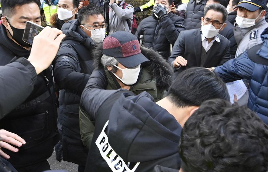 Cho Doo-soon, center, escorted by police officers, arrives home in Ansan, South Korea, Saturday, Dec. 12, 2020. Angry protesters threw eggs and shouted insults as Cho, one of South Korea’s most notorious child predators, was released from a prison in southern Seoul on Saturday at the end of a 12-year term. (Kim Jong-taek/Newsis via AP)