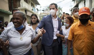 Venezuelan opposition leader Juan Guaidó holds hands with supporters during a visit to La Lucha neighborhood of Caracas, Venezuela, Thursday, Dec. 10, 2020. Guaidó’s coalition is holding a referendum which culminates on Saturday. It asks Venezuelans at home and abroad to say whether they wish to end President Nicolas Maduro’s rule and hold fresh presidential and legislative elections. (AP Photo/Ariana Cubillos)