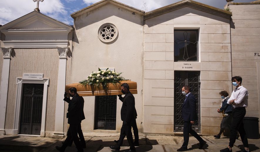 FILE - In this May 12, 2020 file photo, the casket containing the body of Annunziata Ginoble, the mother of Mayor of Roseto degli Abruzzi Sabatino Di Girolamo, third from right, with his sister, Marisa Di Felice, second from right, and his son, Francesco, right, is taken to her burial site inside the small cemetery of Montepagano, central Italy. Italy is poised to reclaim the dishonor of reporting the most coronavirus deaths in Europe, as the second surge ravages the country’s disproportionately old population and exposes how public health shortfalls and delayed restrictions compounded a lack of preparedness going into the pandemic. (AP Photo/Domenico Stinellis, file)