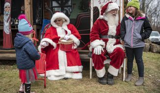 Emma Woods, 3, left,and Rylee Day, 9, right, meet Santa and Mrs. Claus on Saturday, Dec. 5, 2020, at Loveberry&#39;s Tree Farm in Quincy, Mich. (Alyssa Keown/Battle Creek Enquirer via AP)