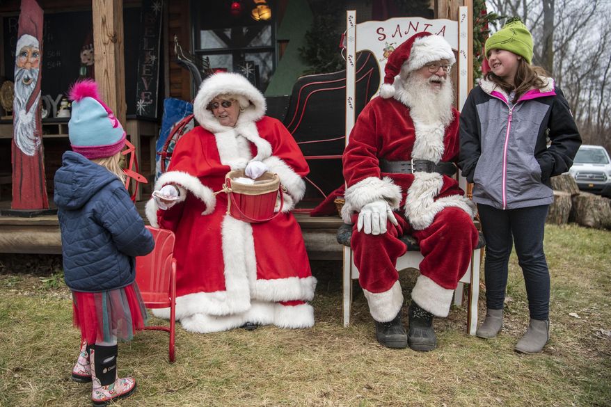 Emma Woods, 3, left,and Rylee Day, 9, right, meet Santa and Mrs. Claus on Saturday, Dec. 5, 2020, at Loveberry&#39;s Tree Farm in Quincy, Mich. (Alyssa Keown/Battle Creek Enquirer via AP)