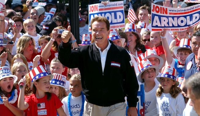 In this Oct. 5, 2003, file photo, Republican candidate for California governor Arnold Schwarzenegger walks up the steps to the state Capitol surrounded by children and waving to supporters during a campaign rally in Sacramento, Calif. (AP Photo/Steve Yeater, File)