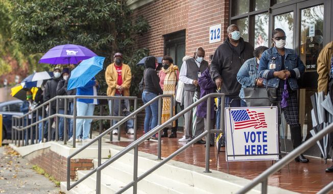 People wait in line on the first day of advance voting for Georgia&#x27;s Senate runoff election at the Bell Auditorium in Augusta, Ga., Monday, Dec. 14, 2020. (Michael Holahan/The Augusta Chronicle via AP)