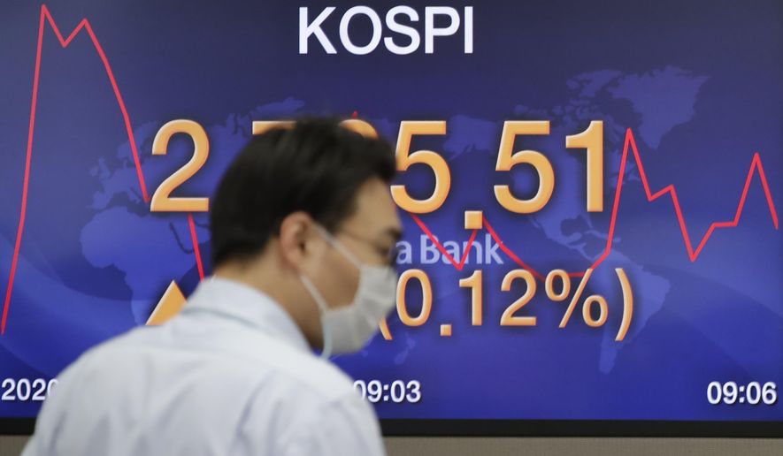 A currency trader walks near the screen showing the Korea Composite Stock Price Index (KOSPI) at the foreign exchange dealing room in Seoul, South Korea, Tuesday, Dec. 15, 2020. Asian shares sank on Tuesday after a lackluster day on Wall Street as investors wait to see if Congress can break a logjam on delivering more aid to people, businesses and local governments affected by the coronavirus pandemic.(AP Photo/Lee Jin-man)