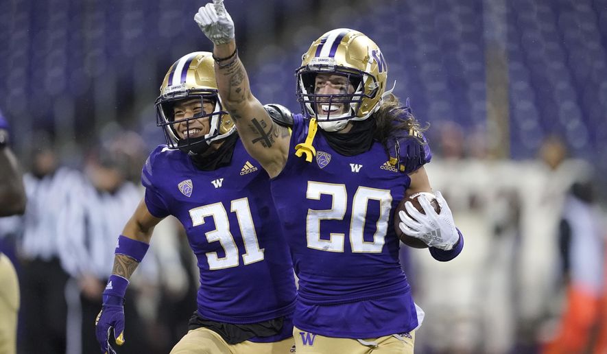 FILE - Washington's Asa Turner (20) celebrates with Kamren Fabiculanan (31) after Turner intercepted a pass in the final minute of an NCAA college football game against Oregon State in Seattle, in this Saturday, Nov. 14, 2020, file photo. Washington won 27-21. Washington has pulled out of the Pac-12 football championship game due to COVID-19 issues in the Huskies program, and Oregon will now play No. 13 USC for the conference title on Friday instead. Washington (3-1) announced Monday, Dec. 14, 2020, it is withdrawing from the championship game after determining the Huskies did not have at least 53 scholarship players available and did not meet the minimum number of scholarship athletes at specific positions.(AP Photo/Ted S. Warren, File)