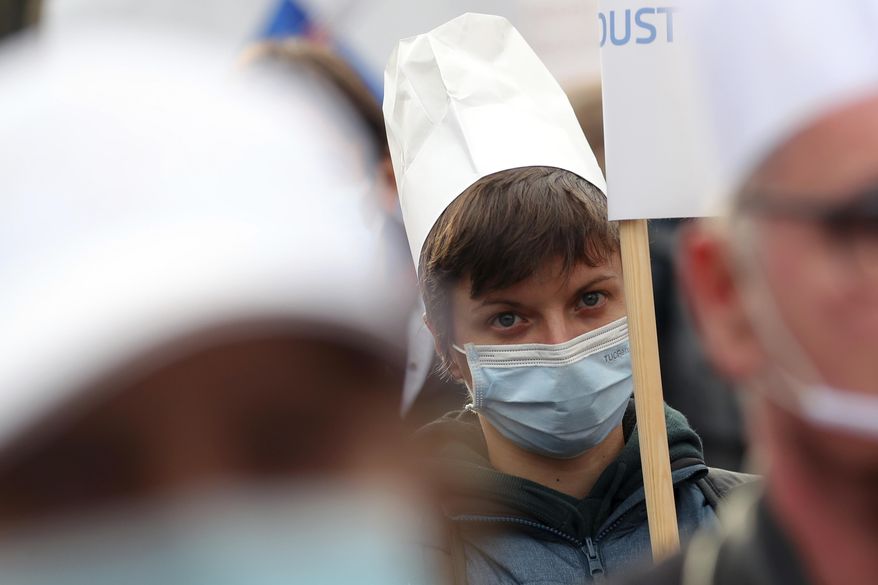 A protester wears a chef's hat, Monday, Dec. 14, 2020 in Paris, as part of a demonstration of hotel and restaurant owners to demand their businesses to reopen. (AP Photo/Thibault Camus)
