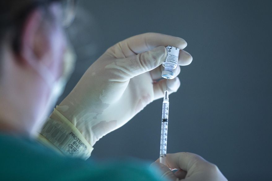 A vial of the Pfizer-BioNTech COVID-19 vaccine is drawn into a syringe, Monday, Dec. 14, 2020, on the 12th floor of the University of Iowa Stead Family Children's Hospital in Iowa City, Iowa. (Joseph Cress/Iowa City Press-Citizen via AP)