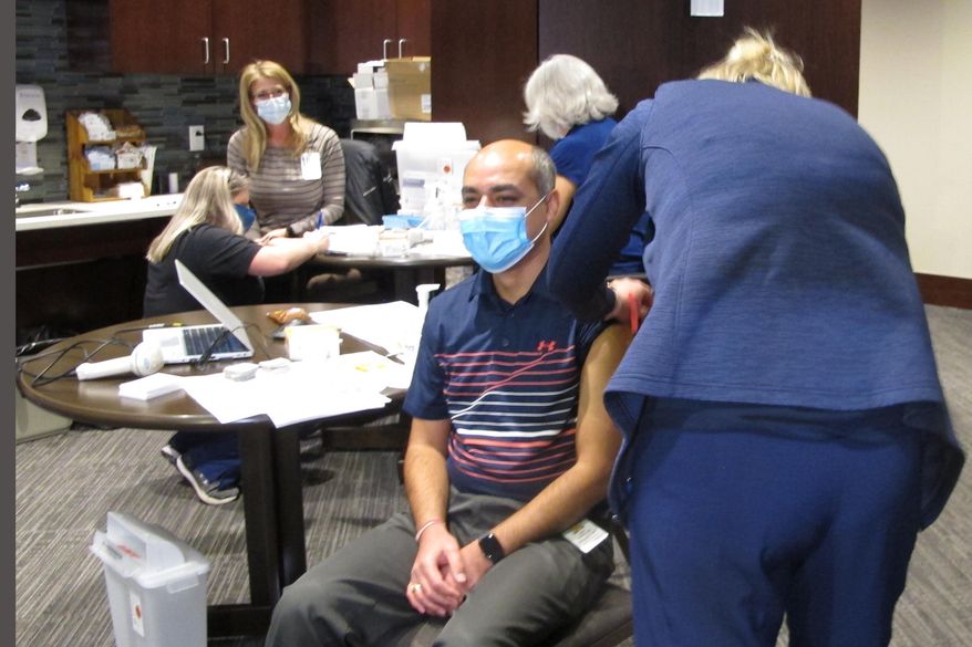 Dr. Avish Nagpal, an infectious disease specialist who has been treating COVID-19 patients at Sanford Health in Fargo, N.D., receives the first shot of the coronavirus vaccine given in North Dakota on Monday, Dec. 14, 2020. The hospital was the first to receive the vaccine in the state and started giving shots to frontline workers in COVID units, intensive care units and emergency departments. North Dakota has been among the worst states in the nation for virus outbreaks. (AP Photo/Dave Kolpack)