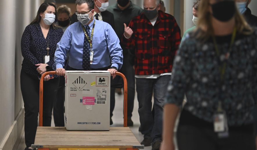 Minnesota Gov. Tim Walz, right, follows the first delivery of the Pfizer-BioNTech COVID-19 vaccines into the Minneapolis Veteran Affairs Hospital Monday, Dec. 14, 2020. (Aaron Lavinsky/Star Tribune via AP)