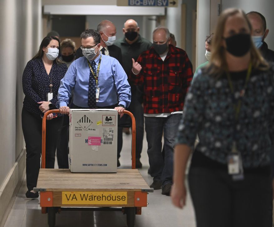 Minnesota Gov. Tim Walz, right, follows the first delivery of the Pfizer-BioNTech COVID-19 vaccines into the Minneapolis Veteran Affairs Hospital Monday, Dec. 14, 2020. (Aaron Lavinsky/Star Tribune via AP)