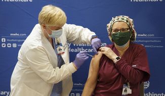 Tami Jeffries, R.N., administers the first locally-available dose of the Pfizer-BioNTech COVID-19 vaccine to ICU respiratory therapist Sue Gallagher at Mary Washington Hospital in Fredericksburg, Va. on Tuesday, Dec. 15, 2020. (Mike Morones/The Free Lance-Star via AP)