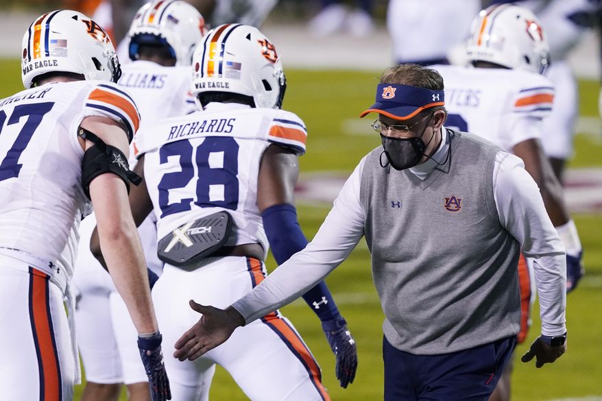 Then Auburn head coach Gus Malzahn wishes players good luck during warmups prior to an NCAA college football game against Mississippi State, Saturday, Dec. 12, 2020, in Starkville, Miss. Auburn athletic director Allen Greene announced the coach's firing on Sunday, Dec. 13, 2020, a day after the Tigers finished the regular season with a 24-10 victory over Mississippi State. (AP Photo/Rogelio V. Solis)