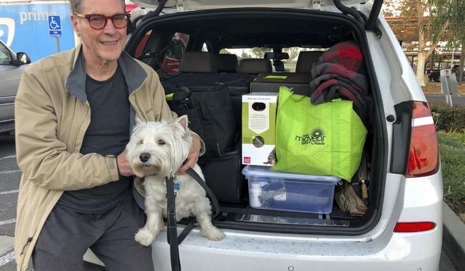 Matt Frinzi, 68, poses with his dog, Whitey, and his car filled with his belongings, in West Sacramento, California, on Tuesday, Dec. 15, 2020. Prinzi has lived in California for 25 years. But Tuesday he officially moved to Reno, Nevada. He said his quality of life has deteriorated so much in California that he wanted to leave. California saw its slowest growth rate on record for the nation&#x27;s most populous state, adding just 21,200 people during the year that ended in July, state officials said Wednesday, Dec. 16, 2020. (AP Photo/Adam Beam)