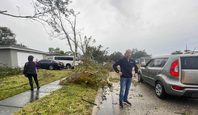 Debris is seen on the ground as residents survey damage along Elmhurst Drive after a possible tornado touched down in the area during a storm Wednesday, Dec. 16, 2020, in Pinellas Park, Fla. (James Borchuck/Tampa Bay Times via AP)