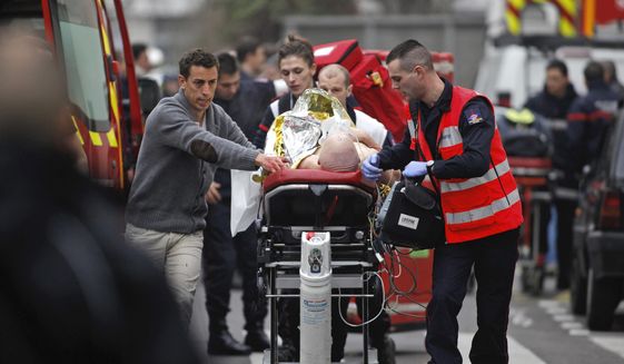 FILE - In this Jan. 7, 2015, file photo, an injured person is transported to an ambulance after a shooting at the French satirical newspaper Charlie Hebdo&#39;s office in Paris, France. The terrorism trial of 14 people linked to the January 2015 Paris attacks on the satirical weekly Charlie Hebdo and a kosher supermarket ends Wednesday after three months punctuated by new attacks, a wave of coronavirus infections among the defendants, and devastating testimony bearing witness to three days of bloodshed that shook France.(AP Photo/Thibault Camus, File)