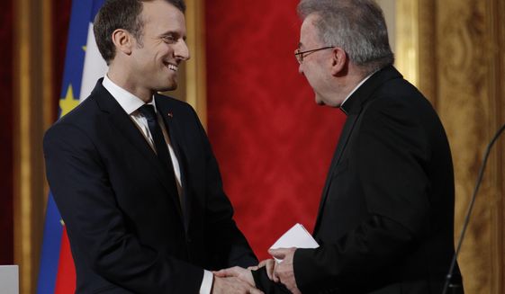 FILE - In this Jan.4, 2018 file photo, French President Emmanuel Macron, left, greets Apostolic Nuncio to France Luigi Ventura, at the Elysee Palace in Paris.A Paris court is expected to hand out its verdict Wednesday on a former Vatican ambassador on trial in France for sexually assaulting five men in 2018 and 2019. (Yoan Valat, Pool via AP, File)