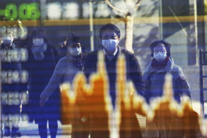 People wearing face masks to protect against the spread of the coronavirus reflected on the electronic board of a securities firm in Tokyo, Wednesday, Dec.16, 2020. Asian shares are higher Thursday, Dec. 17, 2020 on hopes the U.S. Congress may finally deliver fresh aid to help businesses and families weather the pandemic. (AP Photo/Koji Sasahara)