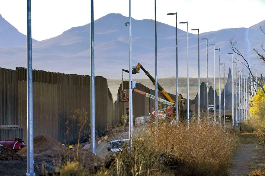 Crews construct a section of border wall in San Bernardino National Wildlife Refuge, Tuesday, Dec. 8, 2020, in Douglas, Ariz.  Construction of the border wall, mostly in government owned wildlife refuges and Indigenous territory, has led to environmental damage and the scarring of unique desert and mountain landscapes that conservationists fear could be irreversible. (AP Photo/Matt York)