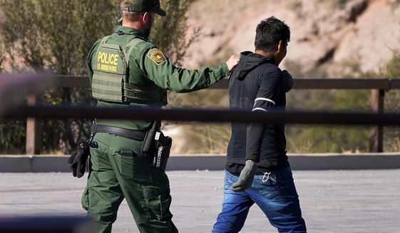 A Customs and Border Patrol agent detains a migrant atop Montezuma&#39;s Pass in Coronado National Memorial, Wednesday, Dec. 9, 2020, in Hereford, Ariz.  Construction of the border wall, mostly in government owned wildlife refuges and Indigenous territory, has led to environmental damage and the scarring of unique desert and mountain landscapes that conservationists fear could be irreversible. (AP Photo/Matt York)