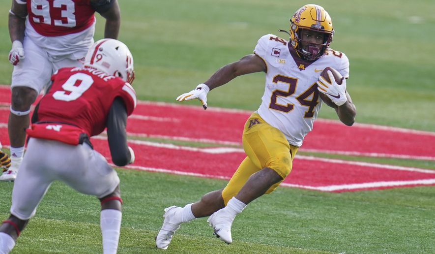 Minnesota running back Mohamed Ibrahim (24) carries the ball away from Nebraska safety Marquel Dismuke (9), during the second half of an NCAA college football game in Lincoln, Neb., Saturday, Dec. 12, 2020. Minnesota won 24-17. (AP Photo/Nati Harnik)
