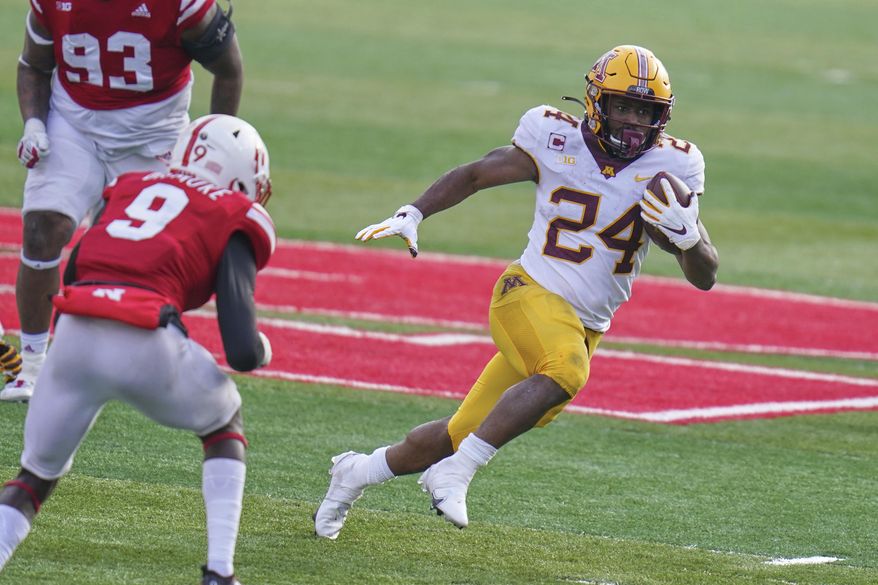 Minnesota running back Mohamed Ibrahim (24) carries the ball away from Nebraska safety Marquel Dismuke (9), during the second half of an NCAA college football game in Lincoln, Neb., Saturday, Dec. 12, 2020. Minnesota won 24-17. (AP Photo/Nati Harnik)
