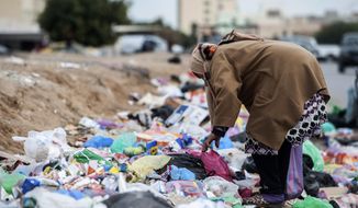 A woman picks through garbage in Kasserine, Tunisia, on Friday Dec. 11, 2020. Hundreds of desperate Tunisians have set themselves on fire over the past 10 years to protest police harassment, poverty or the lack of opportunity in the country. They are following the example of 26-year-old fruit seller Mohammed Bouazizi, whose self-immolation in 2010 led to the downfall of Tunisia’s dictator of 23 years (AP Photo/Riadh Dridi)