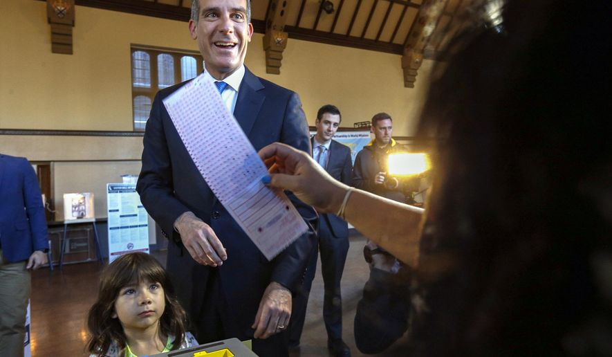 FILE - In this March 7, 2017, file photo, Los Angeles Mayor Eric Garcetti casts his election ballot with his daughter, Maya, in Los Angeles. Garcetti said Thursday, Dec. 17, 2020 that his now 9-year-old daughter, Maya, has tested positive for COVID-19, and that he and his wife are quarantining at home. Garcetti said his daughter Maya felt ill on Monday, developed a fever and tested positive for COVID-19. He said he and his wife, Amy, have tested negative. Garcetti also said that he told the incoming Biden Administration earlier this week that he would not leave Los Angeles. (AP Photo/Nick Ut, File)