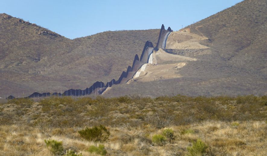 Newly erected border wall separating Mexico, left, and the United States, cuts through through the Sonoran Desert just west of the San Bernardino National Wildlife Refuge, Wednesday, Dec. 9, 2020, in Douglas, Ariz.  Construction of the border wall, mostly in government owned wildlife refuges and Indigenous territory, has led to environmental damage and the scarring of unique desert and mountain landscapes that conservationists fear could be irreversible. (AP Photo/Matt York)