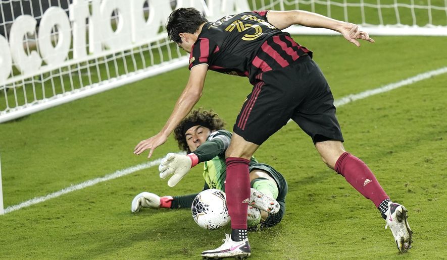 Club America goalkeeper Guillermo Ochoa, lower left, blocks a shot on goal by Atlanta United forward Erick Torres (31) during the second half of a CONCACAF Champions League soccer match, Wednesday, Dec. 16, 2020, in Orlando, Fla. (AP Photo/John Raoux)