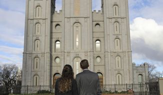 FILE - In this April 6, 2019, file photo, a couple looks at the Salt Lake City temple during the The Church of Jesus Christ of Latter-day Saints&#39; two-day conference. The Church of Jesus Christ of Latter-day Saints added new language to the faith&#39;s handbook Friday, Dec. 18, 2020. imploring members to root out prejudice and racism, adding significance and permanence to recent comments by top leaders on one of the most sensitive topics in the church&#39;s history. (AP Photo/Rick Bowmer, File)