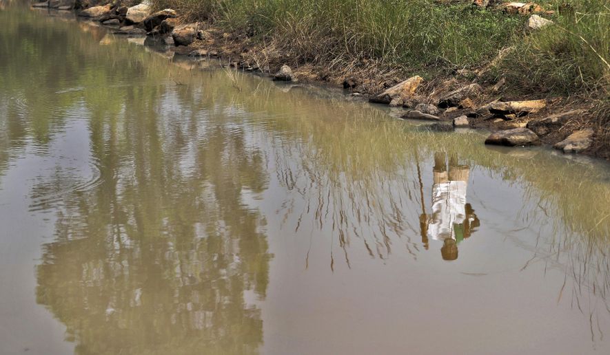 Kalmane Kamegowda, a 72-year-old shepherd, is reflected in a pond he created at a hillock near Dasanadoddi village, 120 kilometers (75 miles) west of Bengaluru, India, Wednesday, Nov. 25, 2020. Kamegowda, who never attended school, says he&#x27;s spent at least $14,000 from his and his son’s earnings, mainly through selling sheep he tended over the years, to dig a chain of 16 ponds on a picturesque hill near his village. (AP Photo/Aijaz Rahi)