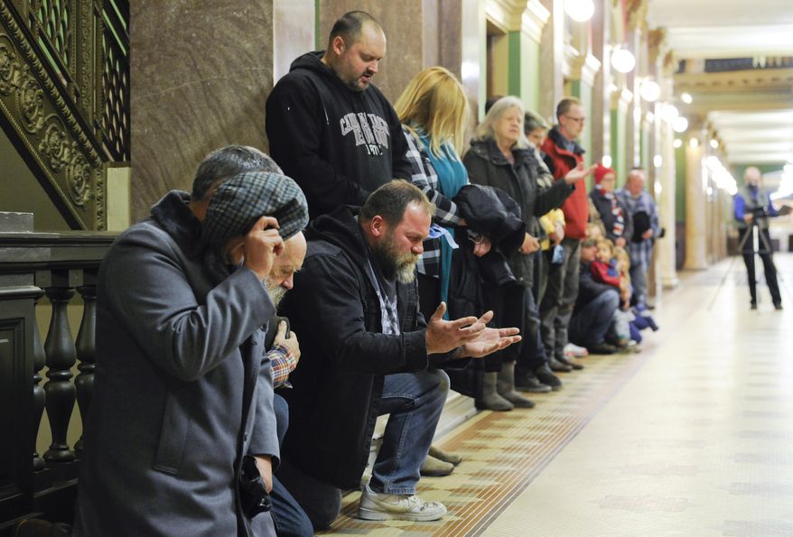 More than two dozen people gathered outside the Montana governor's office in Helena, Mont., on Thursday, Dec, 17, 2020, as part of a peaceful protest of COVID-19 restrictions. At the Capitol, those gathered said the Pledge of Allegiance and The Lord's Prayer. Attendees said they were told not to talk to the media and declined interviews. (Thom Bridge=mehel=