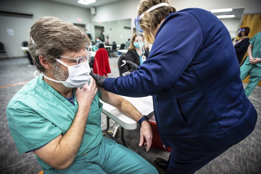 Dr. Lynn Ridgeway, a pulmonologist, pulls up his sleeve as he receives one of the first Pfizer-BioNTech COVID-19 vaccines given to front line workers at Helen Keller Hospital on Thursday, Dec. 17, 2020, in Sheffield, Ala. [Dan Busey /The TimesDaily via AP)