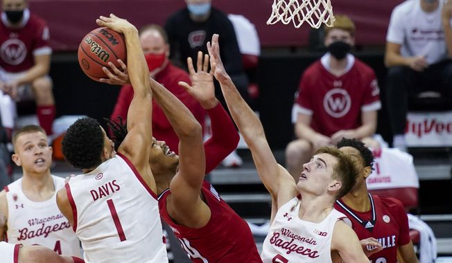 Wisconsin&#x27;s Jonathan Davis (1) blocks a shot by Louisville&#x27;s Jae&#x27;Lyn Withers (24) during the first half of an NCAA college basketball game Saturday, Dec. 19, 2020, in Madison, Wis. (AP Photo/Andy Manis)