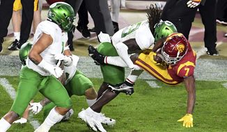 USC Running back Stephen Carr, right, runs for a first down and is tackled by Oregon safety Jamal Hill first half of an NCAA college football game at the Los Angeles Memorial Coliseum in Los Angeles on Friday, Dec. 18, 2020. (Keith Birmingham/The Orange County Register via AP)