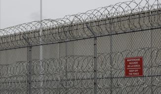 FILE - In this Dec. 16, 2019, file photo, barbed wire fencing is shown behind a sign in English and Spanish in a recreation yard used by detainees during a media tour of the U.S. Immigration and Customs Enforcement detention center, in Tacoma, Wash. A federal judge has declined on Friday, Dec. 18, 2020, to order speedier bail hearings for detainees at the U.S. Immigration and Customs Enforcement lockup in Tacoma, who are especially at risk from COVID-19, despite a few recent cases there. (AP Photo/Ted S. Warren, File)