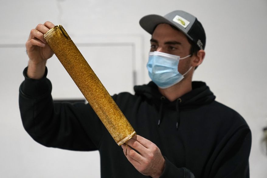 Peter Crimp, kelp supply director for Atlantic Sea Farms, inspects the growth of seaweed spores on a spool of twine at the company's nursery, Tuesday, Dec. 8, 2020, in Saco, Maine. The twine will be wrapped around line and set out to grow in the ocean until harvest time in the spring. (AP Photo/Robert F. Bukaty)