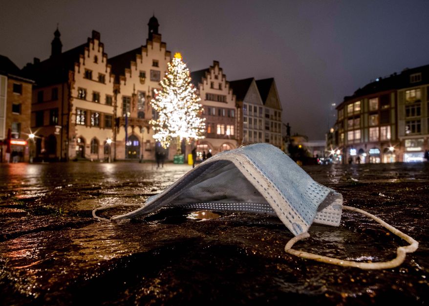 A discarded face mask is seen on the Roemerberg square with the Christmas tree in Frankfurt, Germany, Sunday, Dec. 20, 2020. (AP Photo/Michael Probst)
