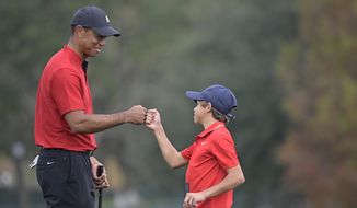 Tiger Woods, left, shares a fist-bump with his son Charlie after putting on the 18th green during the final round of the PNC Championship golf tournament, Sunday, Dec. 20, 2020, in Orlando, Fla. (AP Photo/Phelan M. Ebenhack) **FILE**
