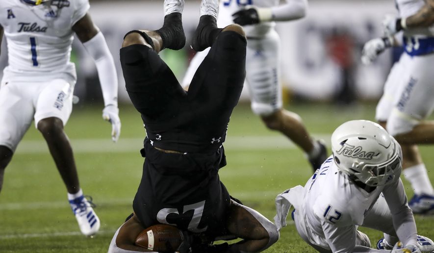Cincinnati running back Cameron Young, left, is tackled by Tulsa cornerback Allie Green IV, right, during the first half of the American Athletic Conference championship NCAA college football game, Saturday, Dec. 19, 2020, in Cincinnati. (AP Photo/Aaron Doster)