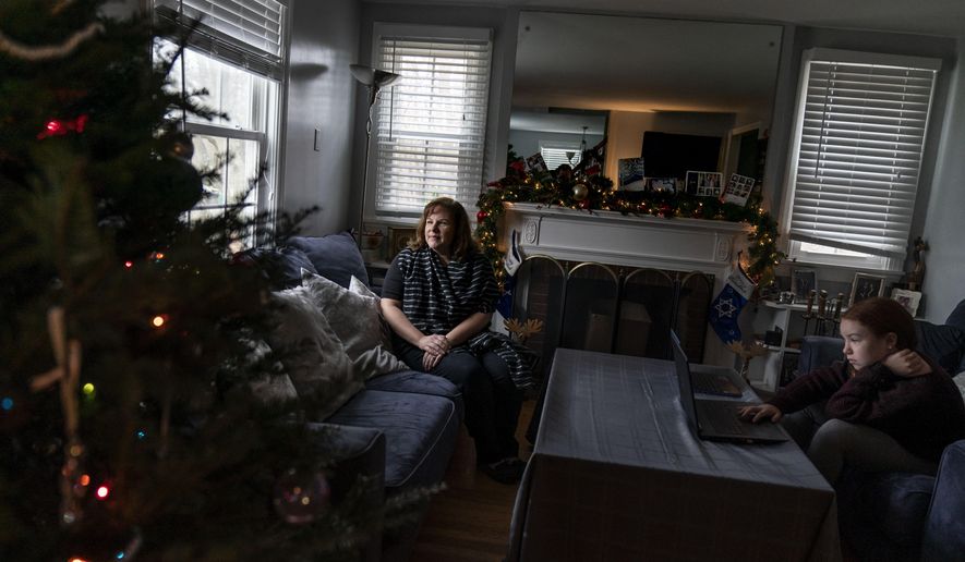 Eileen Carroll, left, sits for a portrait as her daughter, Lily, 11, attends school remotely from their home in Warwick, R.I, Wednesday, Dec. 16, 2020. When Carroll&#39;s other daughter tested positive for the coronavirus, state health officials told her to notify anyone her daughter might have been around. Contact tracers, she was told, were simply too overwhelmed to do it. It&#39;s the same story across the U.S., as a catastrophic surge in infections has made it difficult or impossible to keep up with the calls considered critical to controlling outbreaks. (AP Photo/David Goldman)