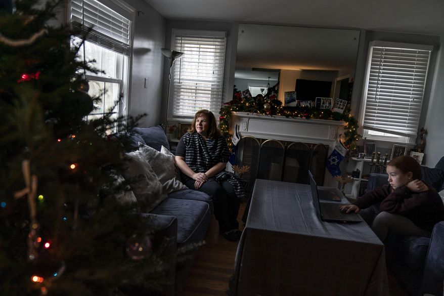 Eileen Carroll, left, sits for a portrait as her daughter, Lily, 11, attends school remotely from their home in Warwick, R.I, Wednesday, Dec. 16, 2020. When Carroll&#39;s other daughter tested positive for the coronavirus, state health officials told her to notify anyone her daughter might have been around. Contact tracers, she was told, were simply too overwhelmed to do it. It&#39;s the same story across the U.S., as a catastrophic surge in infections has made it difficult or impossible to keep up with the calls considered critical to controlling outbreaks. (AP Photo/David Goldman)