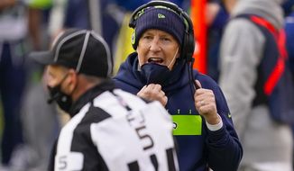 Seattle Seahawks head coach Pete Carroll lowers his face mask to talk to official Jim Quirk (5) during the second half of an NFL football game against the Washington Football Team, Sunday, Dec. 20, 2020, in Landover, Md. (AP Photo/Andrew Harnik)