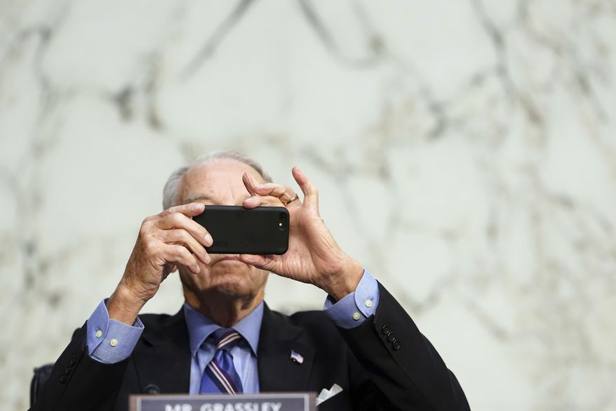 FILE - In this Monday, Oct. 12, 2020 file photo, Sen. Chuck Grassley, R-Iowa, uses his smartphone during a hearing on Capitol Hill in Washington. Researchers from NATO StratCom, a NATO-accredited research group based in Riga, Latvia, paid three Russian companies 300 euros ($368) to buy 337,768 fake likes, views and shares of posts on Facebook, Instagram, Twitter, YouTube and TikTok, including content from verified accounts of Senators Grassley and Chris Murphy. Both senators consented to participate. (Erin Schaff/The New York Times via AP, Pool)